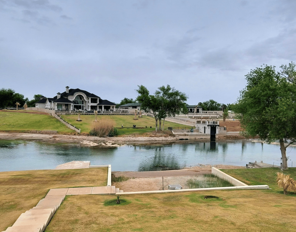 Large green lawn beside a lake with a dock and event pavilion in the background